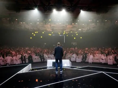 Keynote speaker addressing a full audience at NGSC 2025 under stage lighting